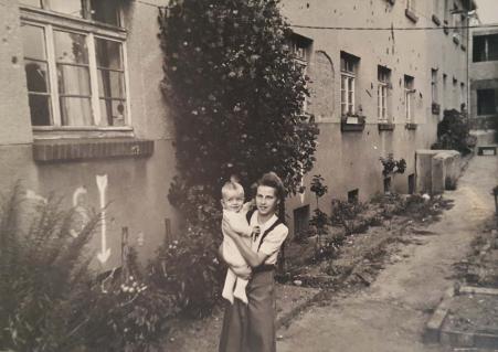 Luise Babisch segurando o filho pequeno de um vizinho no colo, na Alemanha, em 1950. Ao fundo, nota-se o prdio do apartamento onde ela morava danificado pelas bombas da Segunda Guerra Mundial. O prdio ficou partido ao meio.